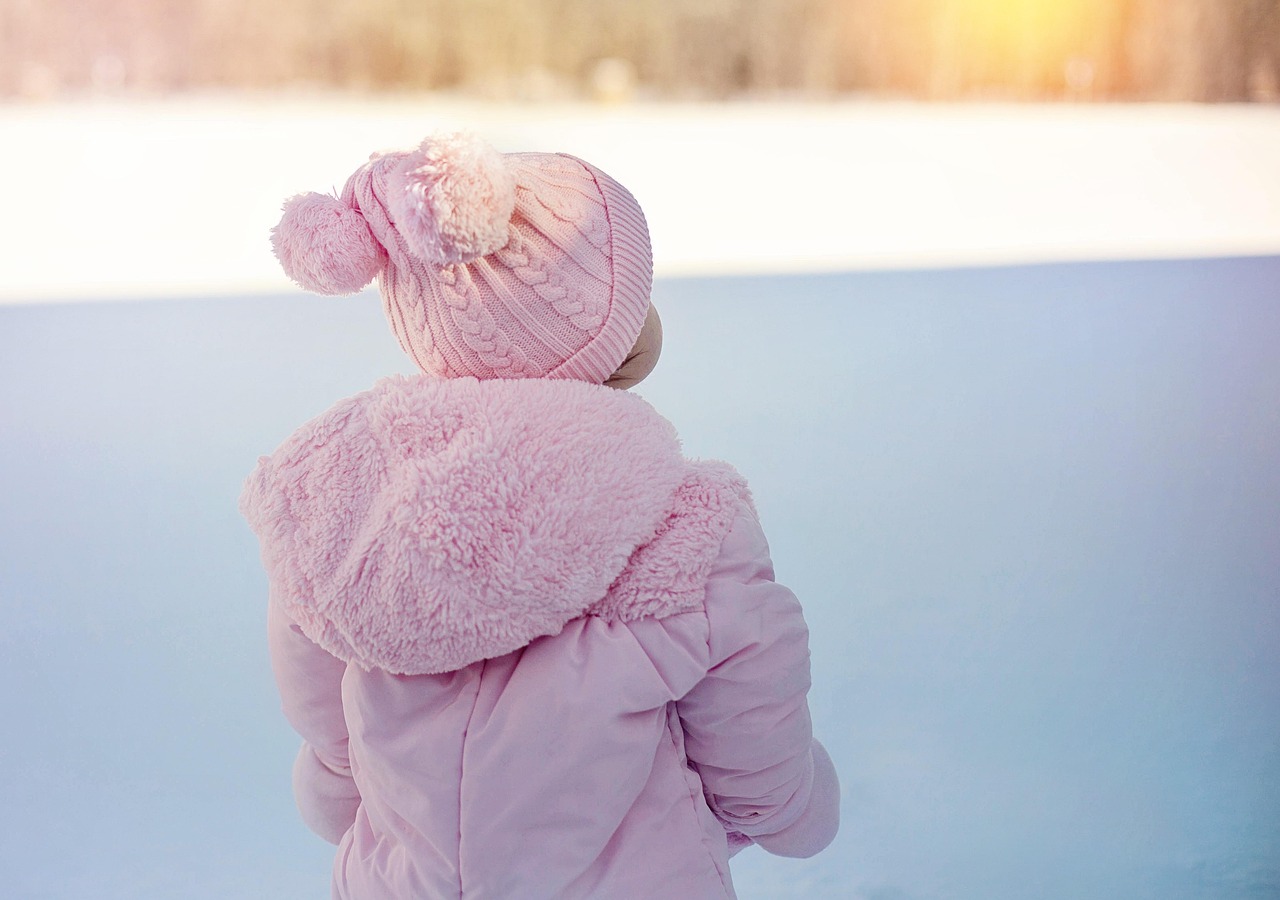 Jeune enfant en combinaison de neige assis dans la poudreuse