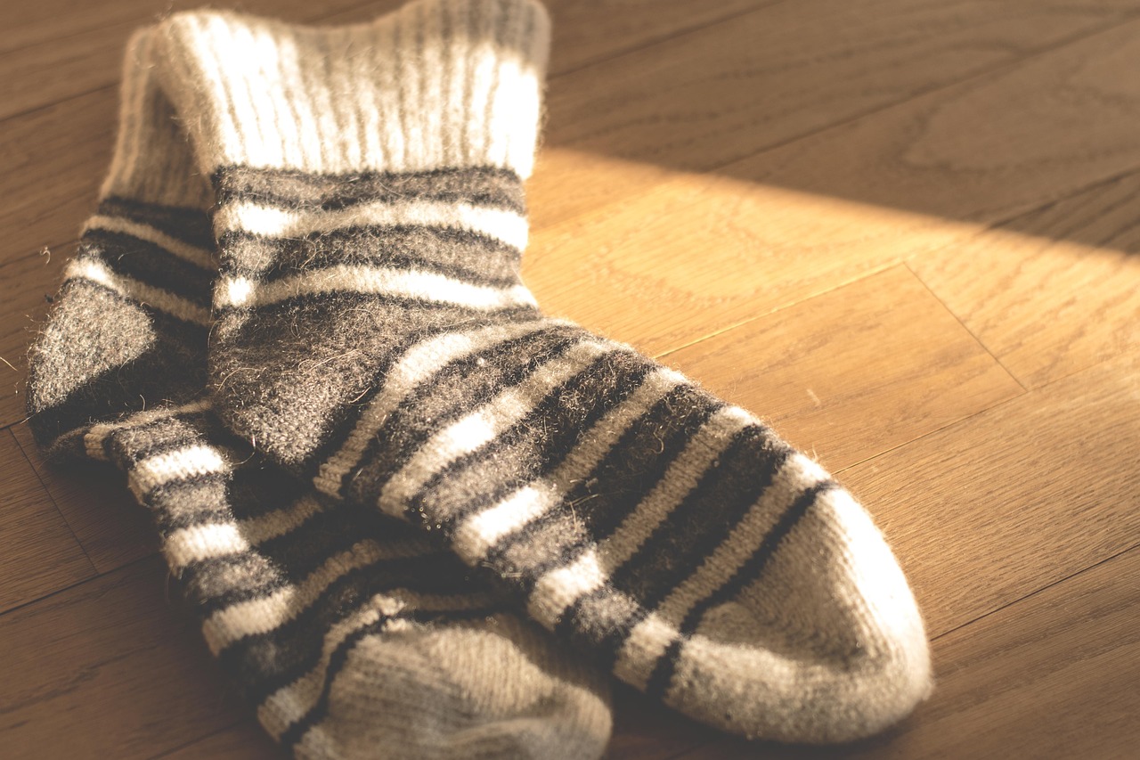 Chaussettes en laine tricotée posées sur un plaid, symbole de la première couche