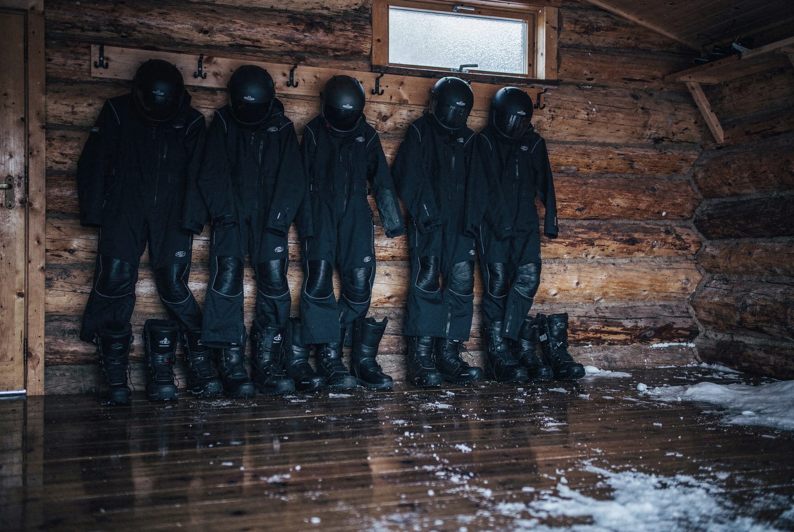 Combinaisons grand froid et casques rangés dans un vestiaire en bois