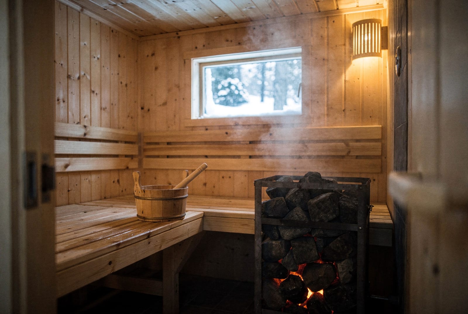 Intérieur d'un sauna finlandais en bois avec son poêle kiuas, seau et louche