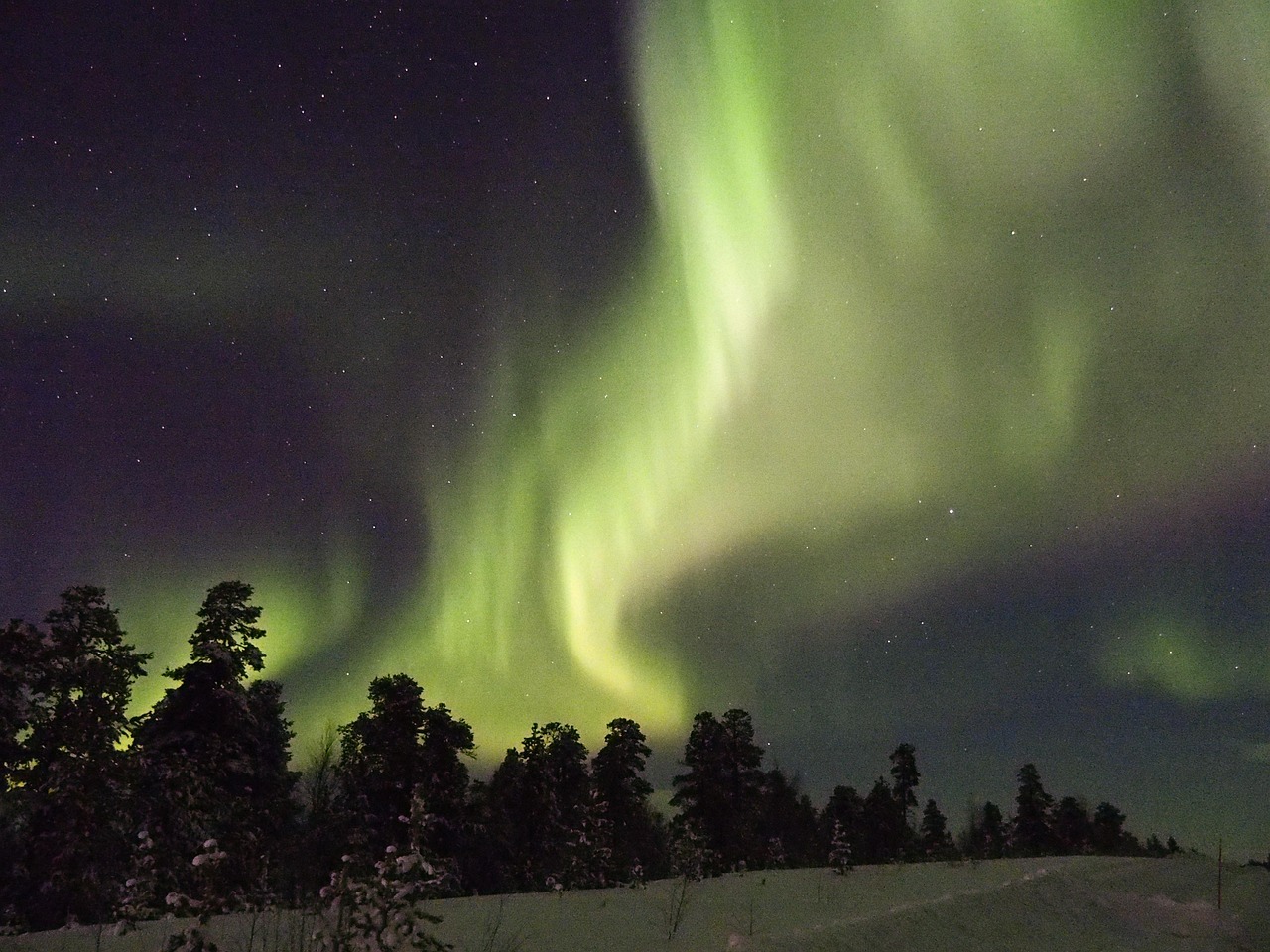 Aurore boréale au-dessus d'un paysage enneigé de Laponie finlandaise